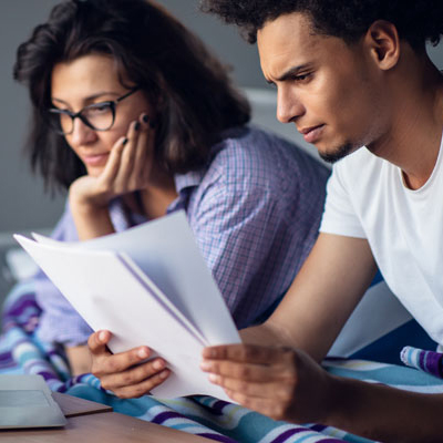 man and woman reviewing paper bill with laptop in front of them